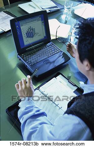 Stock Image - High angle view of a businessman sitting in front of a laptop. Fotosearch