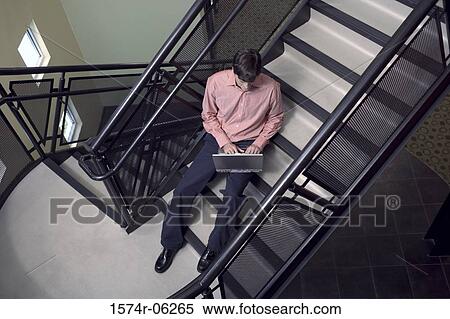High angle view of a businessman sitting on a staircase working on a laptop View Large Photo Image Stock Photography - High angle view of a businessman sitting on a staircase working on a laptop. Fotosearch