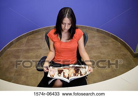 High angle view of a businesswoman sitting in a chair reading a magazine in an office View Large Photo Image Stock Image - High angle view of a businesswoman sitting in a chair reading a magazine in an office. Fotosearch