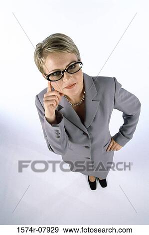 Stock Photo - High angle view of a businesswoman standing with a finger on her face. Fotosearch