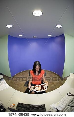 High angle view of a businesswoman sitting in a chair reading a magazine in an office View Large Photo Image Stock Photography - High angle view of a businesswoman sitting in a chair reading a magazine in an office. Fotosearch