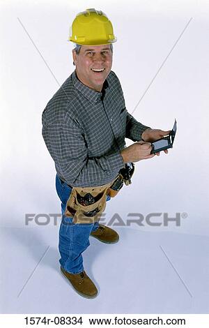 High angle view of a construction worker wearing a hardhat using a hand held device View Large Photo Image Picture - High angle view of a construction worker wearing a hardhat using a hand held device. Fotosearch