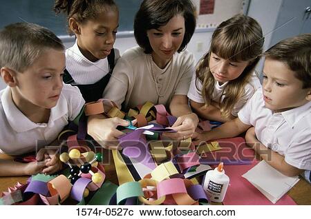 Stock Image - High angle view of a female teacher teaching her students arts and crafts. Fotosearch