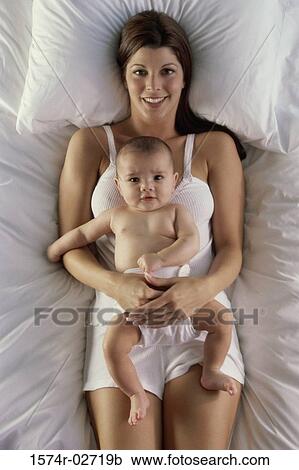 High angle view of a mother lying on a bed with her baby boy View Large Photo Image Stock Image - High angle view of a mother lying on a bed with her baby boy. Fotosearch