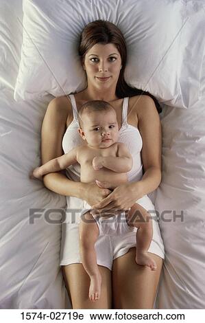 High angle view of a mother lying on a bed with her baby boy View Large Photo Image Stock Image - High angle view of a mother lying on a bed with her baby boy. Fotosearch