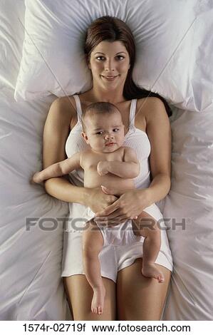 High angle view of a mother lying on a bed with her baby boy View Large Photo Image Stock Image - High angle view of a mother lying on a bed with her baby boy. Fotosearch