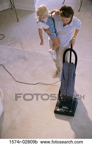 High angle view of a mother vacuuming a rug and carrying her daughter View Large Photo Image Stock Image - High angle view of a mother vacuuming a rug and carrying her daughter. Fotosearch