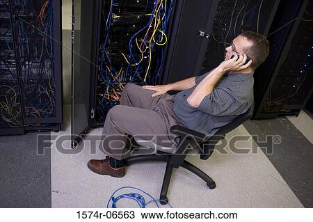 Stock Image - High angle view of a technician talking on a mobile phone in a server room. Fotosearch