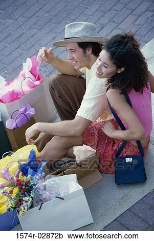 High angle view of a young couple sitting on the sidewalk with shopping bags View Large Photo Image Stock Image - High angle view of a young couple sitting on the sidewalk with shopping bags. Fotosearch