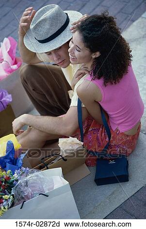 High angle view of a young couple sitting on the sidewalk with shopping bags View Large Photo Image Stock Image - High angle view of a young couple sitting on the sidewalk with shopping bags. Fotosearch