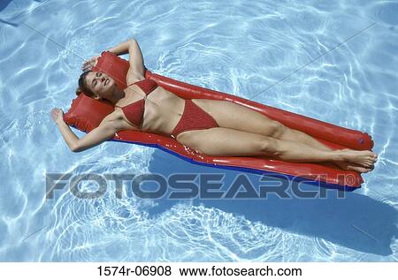 High angle view of a young woman lying on an inflatable raft in a swimming pool View Large Photo Image Stock Photo - High angle view of a young woman lying on an inflatable raft in a swimming pool. Fotosearch