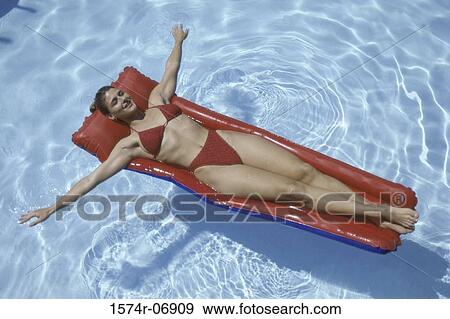 High angle view of a young woman lying on an inflatable raft in a swimming pool View Large Photo Image Stock Photo - High angle view of a young woman lying on an inflatable raft in a swimming pool. Fotosearch