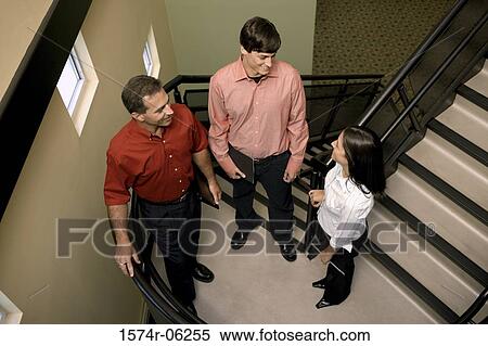 Stock Photography - High angle view of two businessmen and a businesswoman standing on stairs. Fotosearch