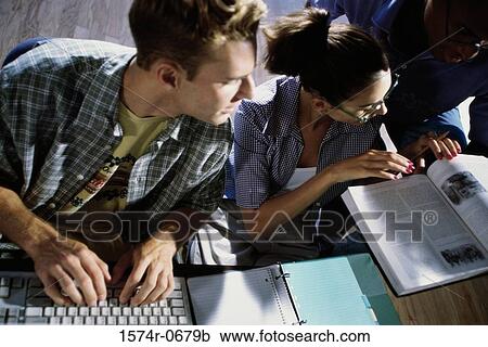 Stock Image - High angle view of two young men and a young woman studying together. Fotosearch