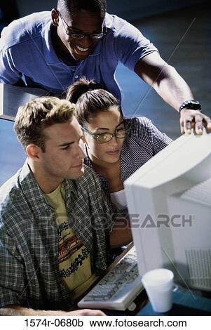 Stock Image - High angle view of two young men and a young woman using a computer. Fotosearch