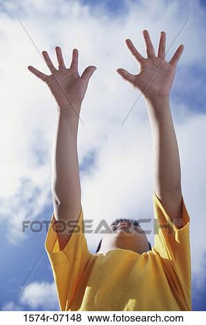 Stock Photo - Low angle view of a boy holding his hands out. Fotosearch