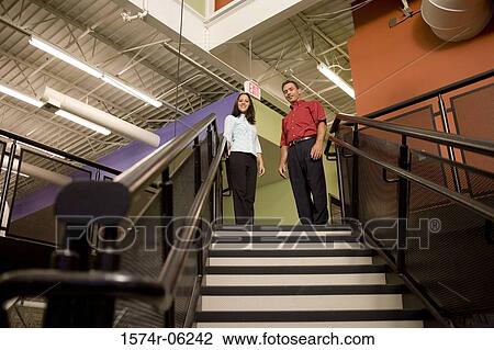 Stock Image - Low angle view of a businessman and a businesswoman standing on stairs. Fotosearch