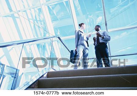 Low angle view of a businessman and a businesswoman talking View Large Photo Image Stock Image - Low angle view of a businessman and a businesswoman talking. Fotosearch