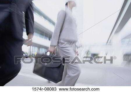 Stock Image - Low angle view of a businessman and a businesswoman walking. Fotosearch