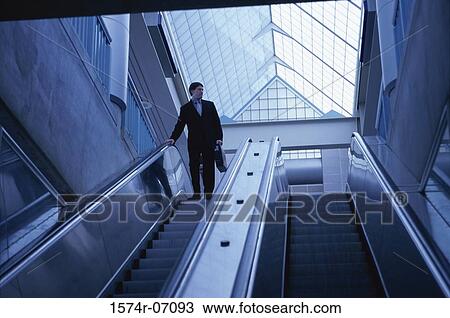 Low angle view of a businessman on an escalator View Large Photo Image Stock Image - Low angle view of a businessman on an escalator. Fotosearch