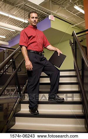 Low angle view of a businessman standing on a staircase View Large Photo Image Stock Image - Low angle view of a businessman standing on a staircase. Fotosearch