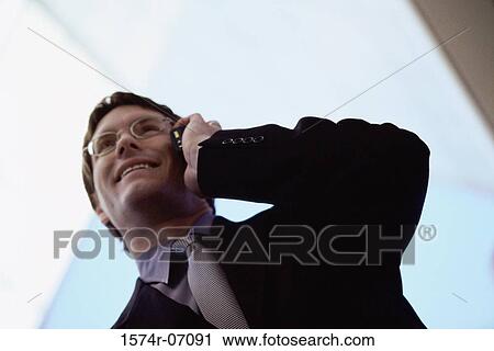 Low angle view of a businessman talking on a mobile phone View Large Photo Image Stock Image - Low angle view of a businessman talking on a mobile phone. Fotosearch