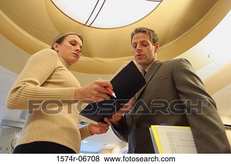Stock Photo - Low angle view of a businessman talking to a businesswoman. Fotosearch