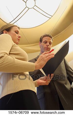 Stock Photo - Low angle view of a businessman talking to a businesswoman. Fotosearch
