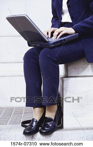 Low angle view of a businesswoman sitting outdoors operating a laptop View Large Photo Image Stock Image - Low angle view of a businesswoman sitting outdoors operating a laptop. Fotosearch