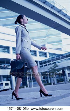 Stock Image - Low angle view of a businesswoman walking with a briefcase. Fotosearch
