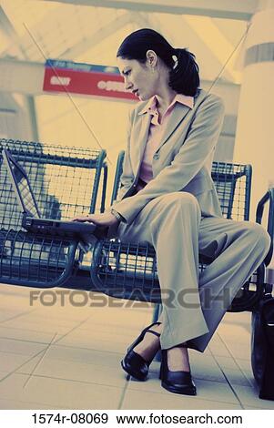Low angle view of a businesswoman sitting while working on a laptop View Large Photo Image Stock Photo - Low angle view of a businesswoman sitting while working on a laptop. Fotosearch