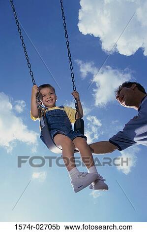 Low angle view of a father pushing his son on a swing View Large Photo Image Stock Image - Low angle view of a father pushing his son on a swing. Fotosearch