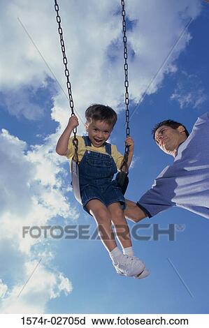 Low angle view of a father pushing his son on a swing View Large Photo Image Stock Image - Low angle view of a father pushing his son on a swing. Fotosearch