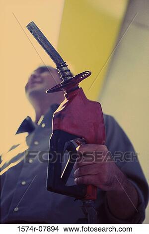 Low angle view of a gas station attendant holding a gas pump nozzle View Large Photo Image Picture - Low angle view of a gas station attendant holding a gas pump nozzle. Fotosearch