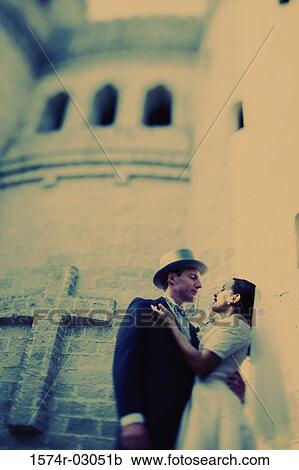 Stock Image - Low angle view of a newlywed couple embracing each other. Fotosearch