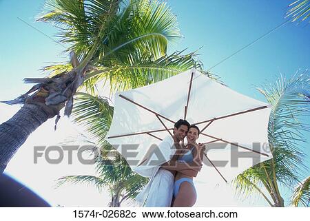 Low angle view of a young couple embracing on the beach View Large Photo Image Stock Image - Low angle view of a young couple embracing on the beach. Fotosearch