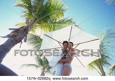 Low angle view of a young couple embracing on the beach View Large Photo Image Stock Photography - Low angle view of a young couple embracing on the beach. Fotosearch