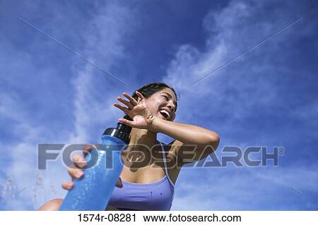 Low angle view of a young woman holding a bottle of water View Large Photo Image Stock Image - Low angle view of a young woman holding a bottle of water. Fotosearch