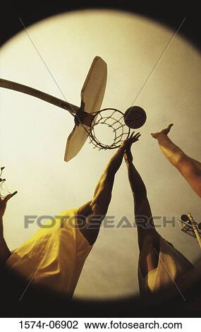 Stock Image - Low angle view of people's hands reaching out for a basketball. Fotosearch
