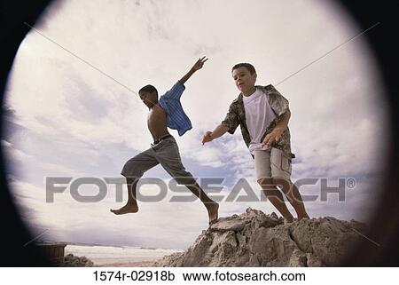 Low angle view of two boys jumping on the beach View Large Photo Image Stock Image - Low angle view of two boys jumping on the beach. Fotosearch