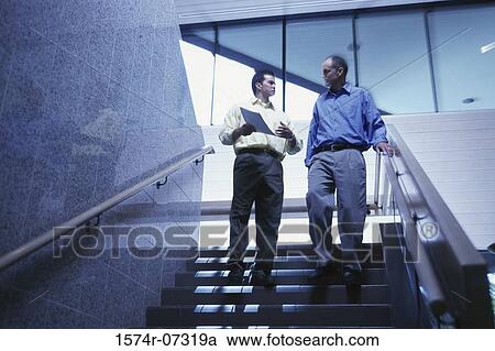 Low angle view of two businessmen walking down stairs View Large Photo Image Stock Image - Low angle view of two businessmen walking down stairs. Fotosearch