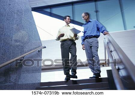 Low angle view of two businessmen walking down stairs View Large Photo Image Stock Image - Low angle view of two businessmen walking down stairs. Fotosearch
