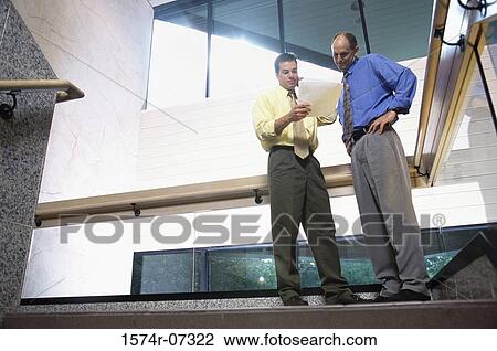 Low angle view of two businessmen discussing on the top of a staircase View Large Photo Image Stock Image - Low angle view of two businessmen discussing on the top of a staircase. Fotosearch