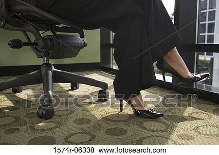 Low section view of a businesswoman sitting on an office chair View Large Photo Image Stock Photo - Low section view of a businesswoman sitting on an office chair. Fotosearch