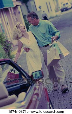Mature couple walking together holding shopping bags View Large Photo Image Stock Image - Mature couple walking together holding shopping bags. Fotosearch