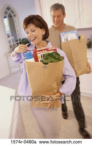 Stock Image - Mid adult couple carrying shopping bags. Fotosearch