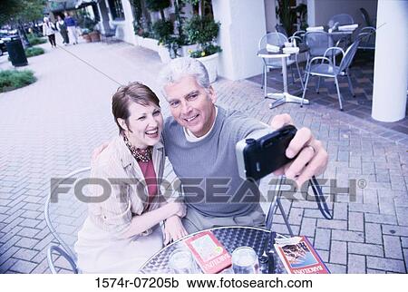 Mid adult couple taking a photograph of themselves View Large Photo Image Stock Image - Mid adult couple taking a photograph of themselves. Fotosearch
