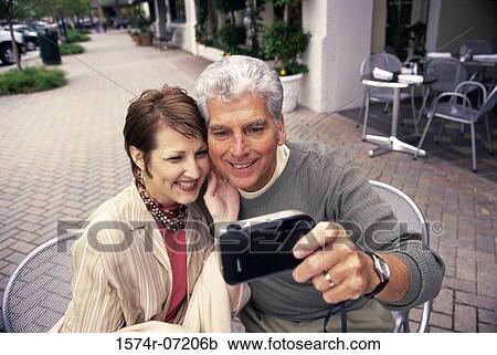 Mid adult couple taking a photograph of themselves View Large Photo Image Stock Image - Mid adult couple taking a photograph of themselves. Fotosearch