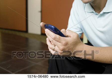 Mid section view of a businessman operating a mobile phone in an office View Large Photo Image Stock Image - Mid section view of a businessman operating a mobile phone in an office. Fotosearch
