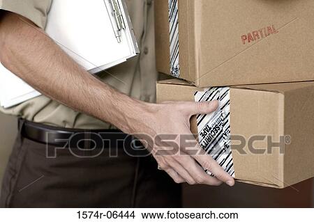Picture - Mid section view of a man holding boxes and a clipboard. Fotosearch